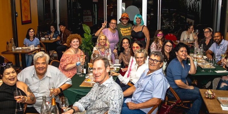 A happy group of people sharing wine and conversation at Thai Bird Alamo Heights.