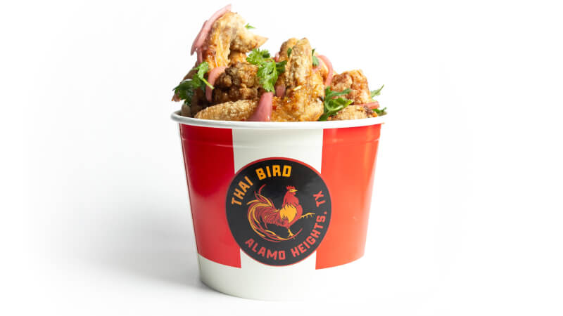 A red and white striped bucket of Thai Jumbo chicken wings