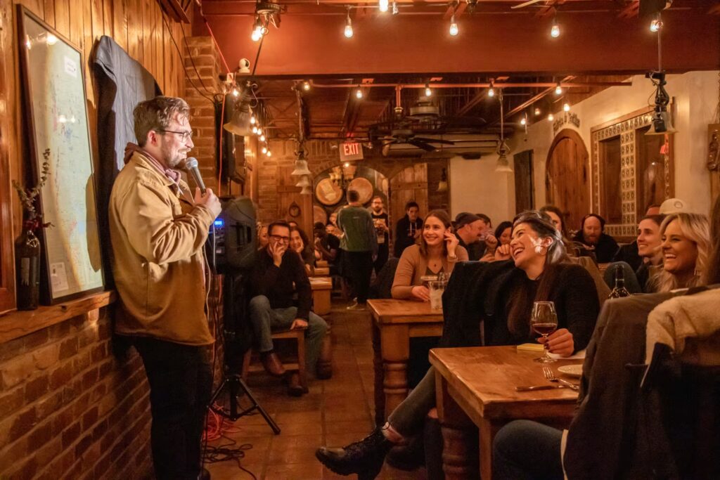 Stand-up comedian performing live in front of a seated audience at a comedy show