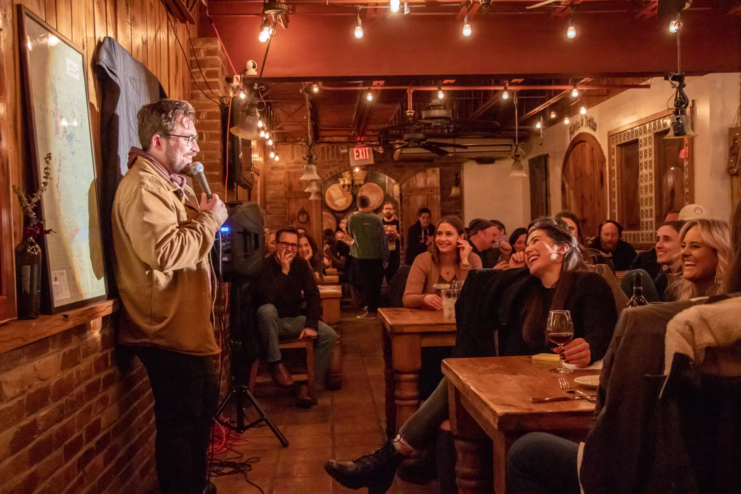 Stand-up comedian performing live in front of a seated audience at a comedy show