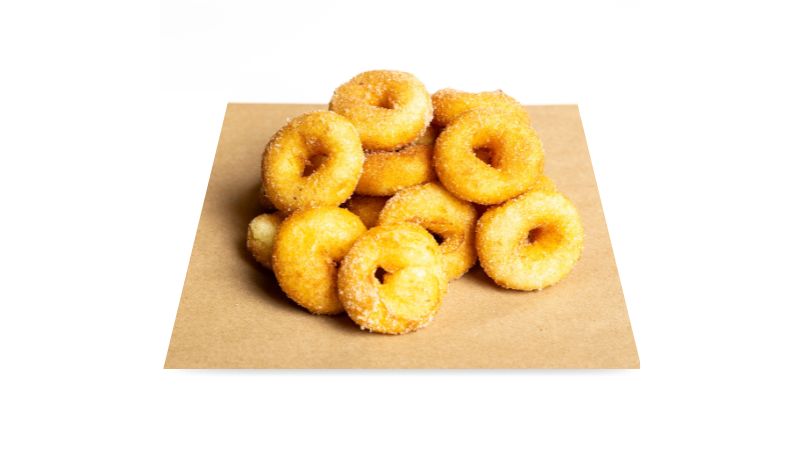 A paper sheet topped with gluten-free fluffy mini donuts, made to order.