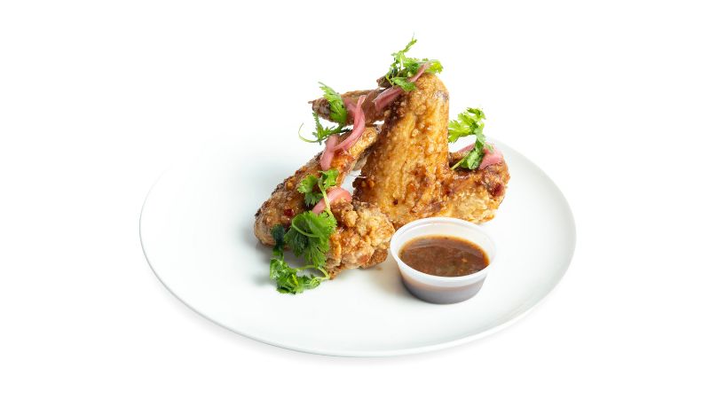 A plate of crispy wings tossed in our tangy tamarind-ginger sauce with pickled onion and herbs.
