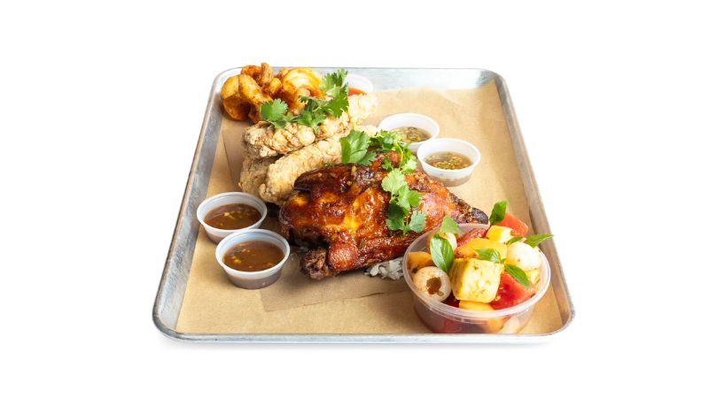 A metal tray holding three crispy tenders and half of a juicy rotisserie chicken.