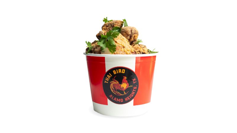 A red and white bucket of crispy bone-in chicken with bold Thai-inspired flavor.