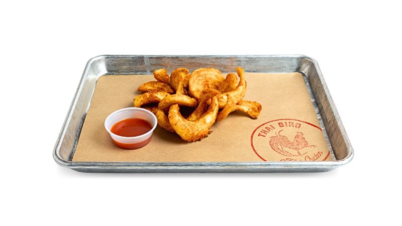 A metal tray of signature fries tossed in chili-lime seasoning.